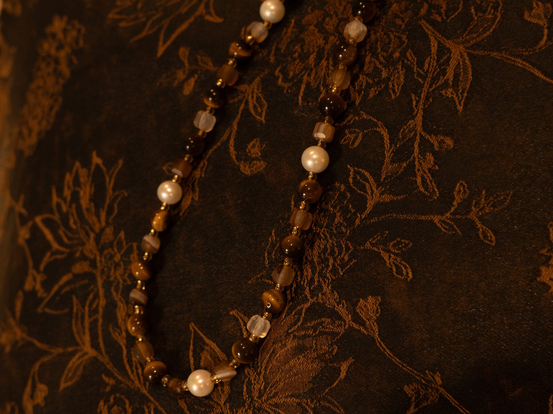 Natural stone necklace details against dark fabric