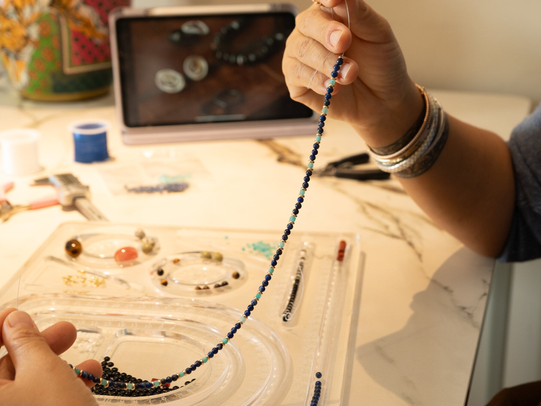A KINGRAX necklace being hand-strung in the studio
